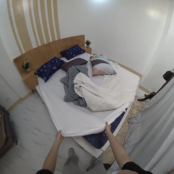 First-person bed making with both hands visible